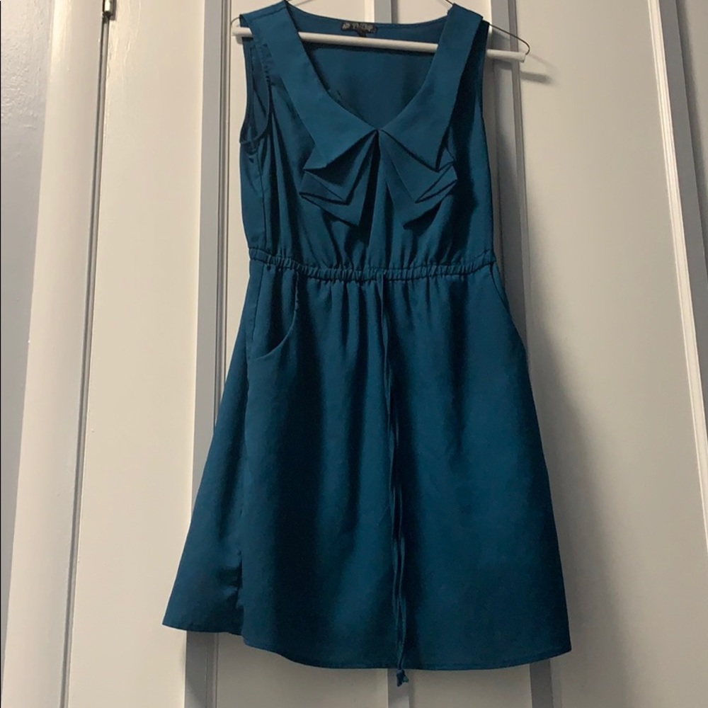 Teal dress with sleek hidden pockets .